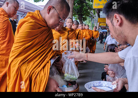 Buddhistische Mönche auf ihren frühen Morgen Almosen runde queuing Almosen von Gläubigen in der Hoffnung zu gewinnen spirituelle Verdienste (Tham Boon); Bangkok, Thailand zu erhalten Stockfoto