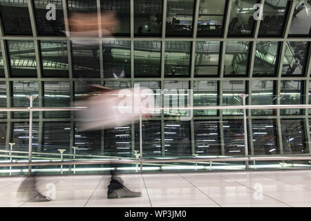 Ein Mann mit Gepäck in verschwommene Bewegung am Flughafen in Halle. Abstraktes Bild von Reisenden in der Lobby. Stockfoto