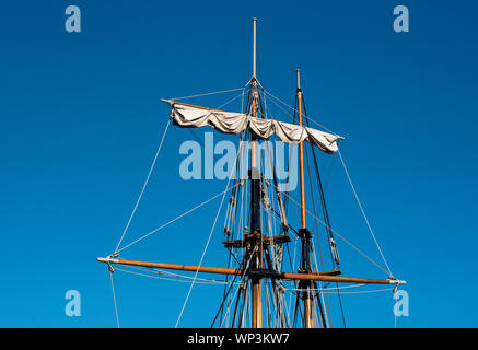 Holzmasten aus zwei hohen Schiffe oder Segelboote mit Hof arm oder Spar und Takelage gegen einen sonnigen blauen Himmel Hintergrund Stockfoto