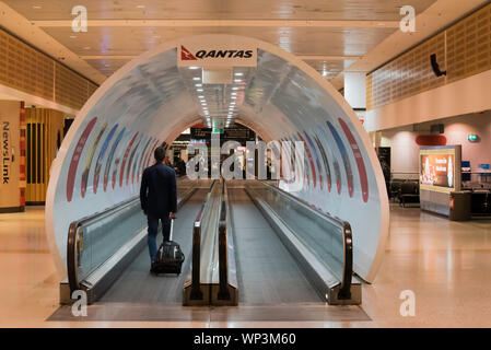 Ein Reisender reitet auf einem Fahrsteig in der Qantas Sydney Domestic Terminal durch eine gefälschte Qantas jet Flugzeug in Sydney Kingsford Smith Flughafen abgedeckt Stockfoto