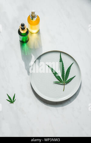 Glasflaschen mit CBD Öl, THC Tinktur und Hanf Blätter auf einem Marmor Hintergrund. Kopieren Sie Raum, mockup. Kosmetik CBD Öl. Stockfoto