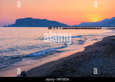 Szenische Ansicht vom Strand im Sonnenuntergang in Alanya, in der Türkei. Im Hintergrund der Halbinsel Alanya Stockfoto