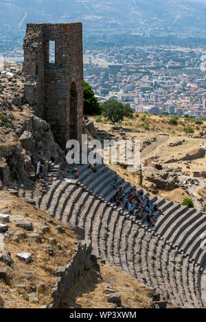 Touristen sitzen unter den Ruinen des römischen Theaters an der antiken Stätte von Pergamon (Pergamon), sitzt über der modernen Stadt Bergama in der Türkei. Stockfoto