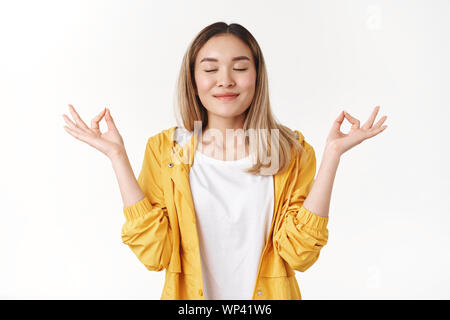 Mädchen fühlen sich entspannt freudige Ruhe. Attraktive Ruhige asiatische blonde Schüler sammeln, Mut, Geduld Atemluft schließen Augen lächeln erfreut, halten Händchen zen Stockfoto