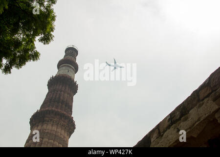 Low-Angle-Ansicht eines Turms gegen Flugzeug fliegen in den Himmel, Qutub Minar, Neu-Delhi, Indien Stockfoto