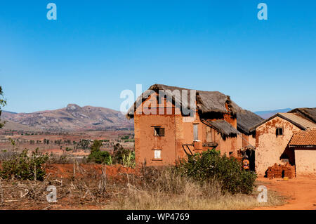 Typische traditionelle lehmziegel aus lehmziegeln gebaut strohgedeckten zweistöckigen Häusern in einem kleinen Dorf im zentralen Hochland von Madagaskar. Tief orange braune Ziegel Stockfoto