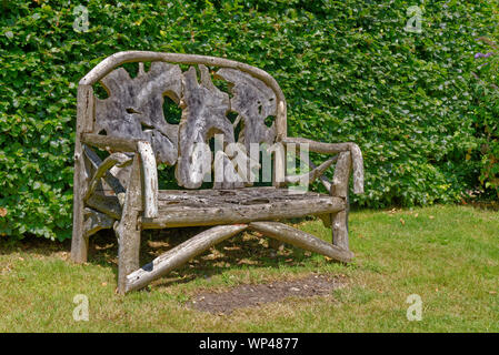 Reich verzierte, rustikal, Holz garten Sitzbank aus recyceltem Holz- teilen, vor einem grünen Pflanzen Wand-Berkshire, Großbritannien Stockfoto