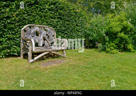 Reich verzierte, rustikal, Holz garten Sitzbank aus recyceltem Holz- teilen, vor einem grünen Pflanzen Wand-Berkshire, Großbritannien Stockfoto