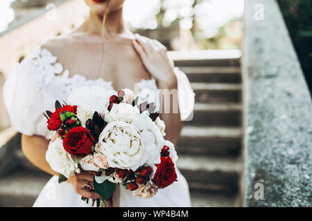 Wedding Bouquet mit roten und weißen Blumen in der Hand der Braut. Close Up, kein Gesicht gesehen. Stockfoto