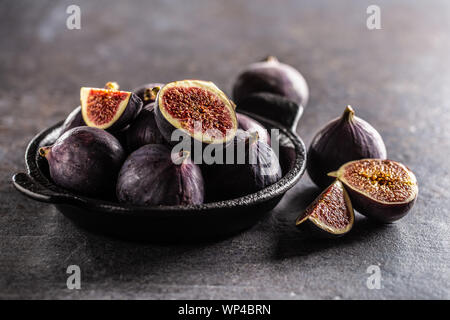 Ein paar Feigen in einem schwarzen Schüssel auf eine dunkle konkrete Tabelle Stockfoto