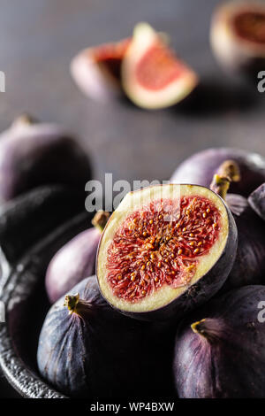 Ein paar Feigen in einem schwarzen Schüssel auf eine dunkle konkrete Tabelle Stockfoto