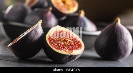 Ein paar Feigen in einem schwarzen Schüssel auf eine dunkle konkrete Tabelle Stockfoto