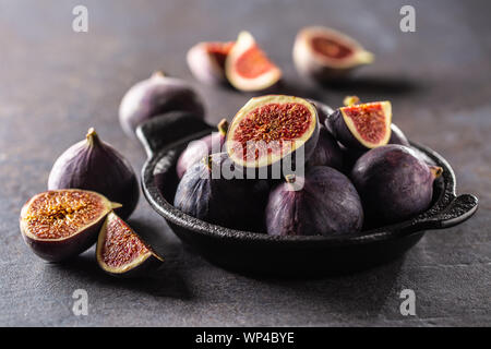 Ein paar Feigen in einem schwarzen Schüssel auf eine dunkle konkrete Tabelle Stockfoto