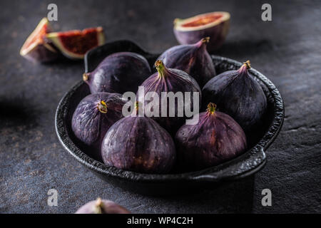 Ein paar Feigen in einem schwarzen Schüssel auf eine dunkle konkrete Tabelle Stockfoto