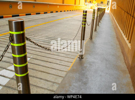 Metallzaun mit Kette entlang der Fußgängerzone. Balustrade trennt Seite gehen von der Straße. Stockfoto