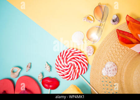 Strand Zubehör auf Mint gelb Hintergrund mit kopieren. Ansicht von oben in beige Stroh Sonnenhut, Handtuch, Sonnenbrille, pink Flip Flops, Kopftuch, Muscheln Stockfoto