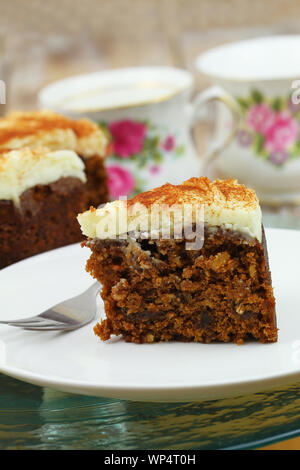 Köstliche Walnuß und Karottenkuchen mit Marzipan Sahnehäubchen auf weiße Platte, Nahaufnahme Stockfoto