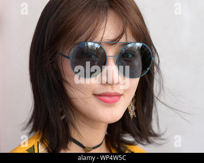 Junge thailändische Schönheit trägt übergroße Runde retro Sonnenbrille. Stockfoto