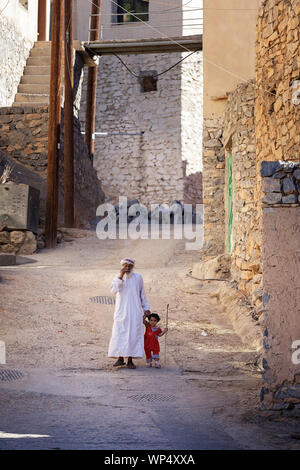 Mein Großvater und mein kleines Mädchen Hand in Hand beim Gehen auf einer idyllischen Straße von einem Dorf in der Nähe von Nizwa, Oman Stockfoto