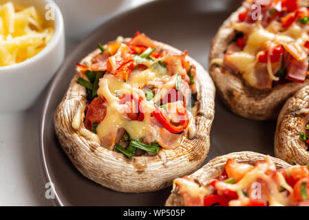 Champignons gefüllt mit Speck, Tomaten, Paprika, Schnittlauch und Käse. Stockfoto