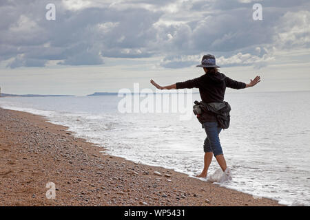 UK Wetter: West Bay Beach, Dorset, England. 7. September 2019. Eine Dame die Energie aus dem Jurassic Küste an einem warmen, sonnigen Morgen, als sie barfuss im Meer des englischen Kanals Paddles. Stockfoto