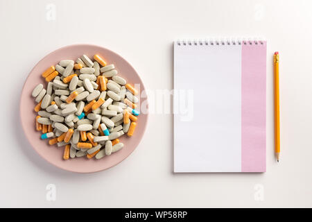 Mit Nahrungsergänzungsmitteln und Notebook Platte, auf weißem Hintergrund. Flach. Stockfoto