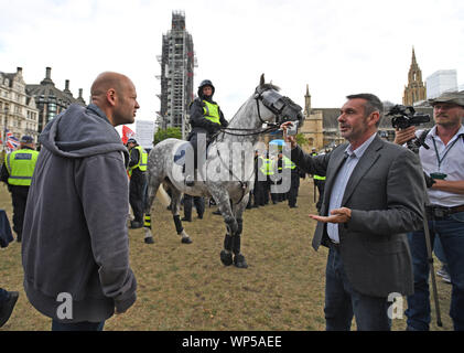 Eine pro-Brexit Demonstrant (links) spricht mit Kommentator Paul Mason außerhalb des Houses of Parliament in Westminster, London. Stockfoto