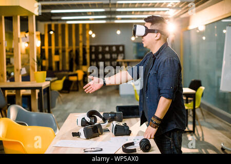 Profil von chinesischen Geschäftsmann im Casual tragen 3d Headset Gläser in Büro, gestikulierte, als ob Händeschütteln mit jemand während in der modernen stehend Stockfoto