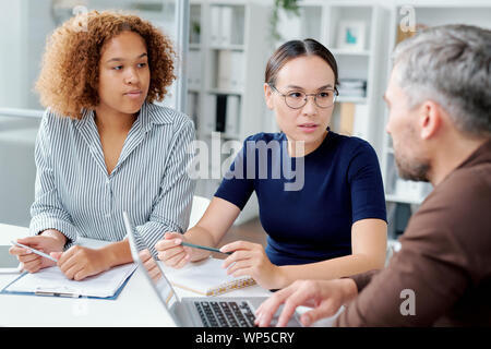 Zwei junge interkulturellen weiblichen Untergebenen Beratung mit Ihrem Chef Stockfoto