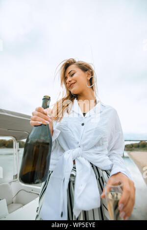 Ein luxuriöses reiche Frau funs Yacht und Holding Flasche Champagner Stockfoto