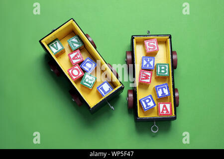 Spielzeugeisenbahn mit Alphabet Würfel auf grünem Hintergrund Stockfoto