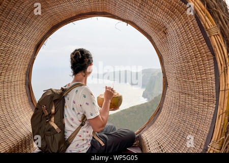 Junge Frau eine Pause und trinken Sie eine Kokosnuss Vor dem Meer, Bali, Indonesien Stockfoto