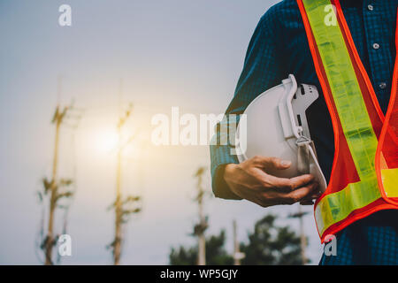 Engineering hält weiß Sicherheit Hüte und elektrische Pole Hintergrund Stockfoto