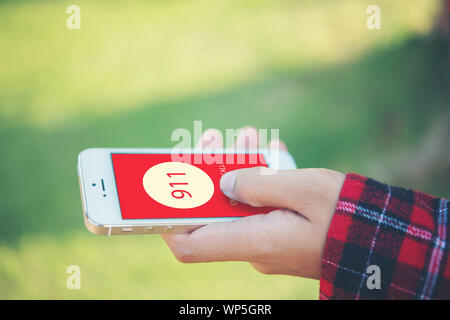 Frau mit einem Smartphone wählen Sie die Notrufnummer auf dem Bildschirm. Grafiken auf dem Bildschirm. Stockfoto