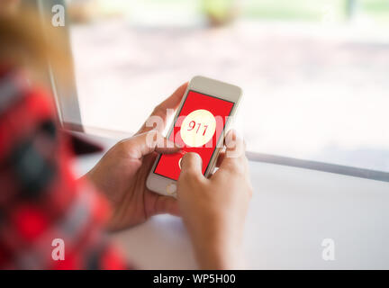 Frau mit einem Smartphone wählen Sie die Notrufnummer auf dem Bildschirm. Grafiken auf dem Bildschirm. Stockfoto