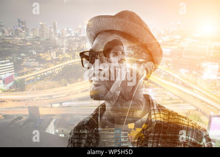 Junge hipster Mann in Ohrhörer holding Smartphone auf dem weißen Hintergrund. Stockfoto