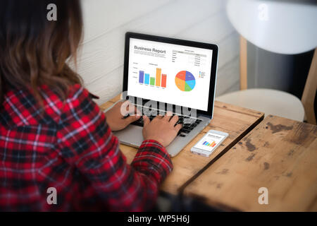 Nahaufnahme der Rückseite einer jungen Geschäftsfrau, die im Büro arbeitet, Tippen auf den Bildschirm mit Diagrammen. Business Finance-Konzept. Stockfoto