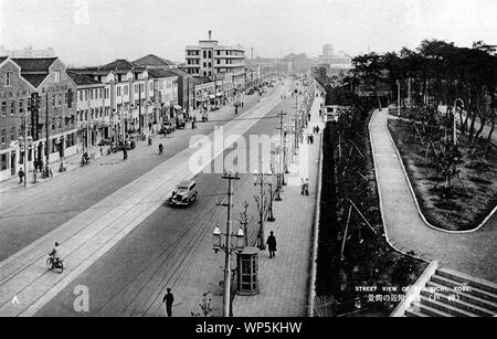 [1920s Japan - Street View von Kobe] - Blick nach Süden hinunter Takimichi Straße (滝道), jetzt bekannt als Blume Straße (フラワーロード), in Kobe, Hyogo Präfektur. Takimichi, buchstäblich Wasserfall Straße, wurde so genannt, weil er die ehemalige Bank von Ikutagawa River (生田川), die durch Nunobiki fällt (布引の滝) zugeführt wurde. Auf der rechten Seite ist die Erholung Boden gebaut für ausländische Einwohner von Kobe. Diese ist nun bekannt als Higashi Yuenchi Park (東遊園地). 20. jahrhundert alte Ansichtskarte. Stockfoto