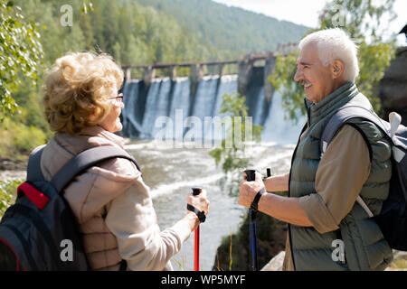 Gerne reifer Mann und Frau in Activewear sprechen in natürlicher Umgebung auf Reise Stockfoto