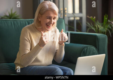 Überglücklich reife Frau fühlen sich euphorisch mit Laptop Stockfoto