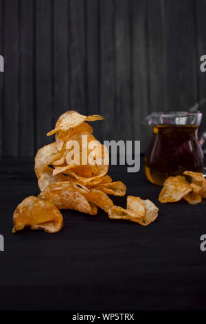 Lecker geröstete Chips mit Olivenöl auf schwarzem Holz- Hintergrund. Stockfoto