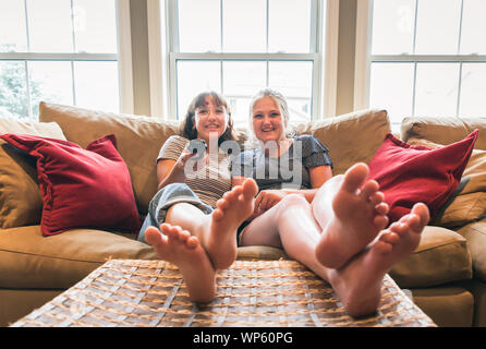 Zwei Mädchen sitzen auf der Couch mit Füßen bis Fernsehen. Stockfoto