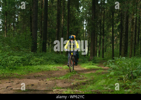 Männliche bikepacker Fahrten entlang eines breiten Schmutz Pfad in den Wald Stockfoto