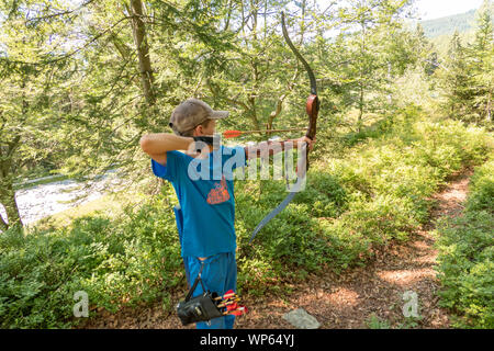 Junge mit Kappe und blaues Hemd Schießen Bogen Stockfoto
