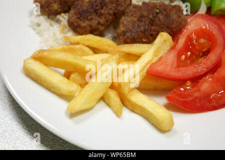 Eine Platte mit Frikadellen mit Pommes Frites, Reis, Gemüse Stockfoto
