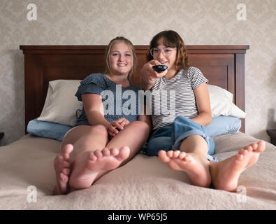 Zwei Mädchen sitzen auf einem Bett fernsehen beobachten. Stockfoto