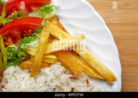 Eine Platte mit Frikadellen mit Pommes Frites, Reis, Gemüse auf dem hölzernen Tisch Stockfoto