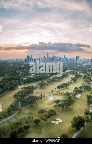 Golf und die Skyline von Manila, Philippinen, in einem schönen Sonnenuntergang. Stockfoto