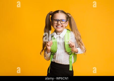 Glückliche Schülerin posiert an der Kamera, gelben Hintergrund, Studio Shot lächelnd Stockfoto