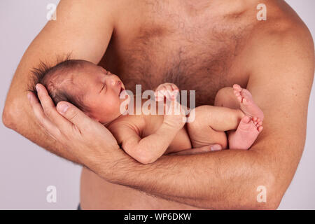 Neugeborene schlafen in die Arme des Vaters auf grauem Hintergrund Stockfoto